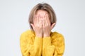 Young european woman in yellow sweater hides her face Royalty Free Stock Photo