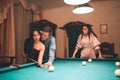 Young european woman look at couple playing billiard. She jelaous. Model is insane. Young man help asian woman to play game.