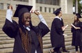 Young excited african american girl student in a university graduate gown and diploma in hands. Royalty Free Stock Photo
