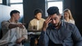 Young excited arab guy student sitting in classroom cannot concentrate on lesson being ridiculed by classmates suffering Royalty Free Stock Photo