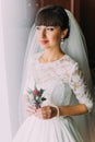 Young excited bride posing with cute floral boutonniere in dressing room before wedding