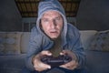 Young excited and concentrated man at home playing videogames holding controller looking stressed and focused in video gaming