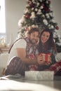 A young excited couple in love sitting on the floor amazed by Xmas presents. Christmas, relationship, love, together Royalty Free Stock Photo