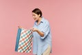 Young excited female in casualwear looking at surprise in open paperbag