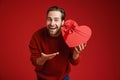 Young excited man exclaiming while showing heart gift box