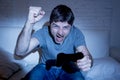 Young excited man at home sitting on living room sofa playing video games using remote control joystick Royalty Free Stock Photo