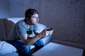 Young excited man at home sitting on living room sofa playing video games using remote control joystick Royalty Free Stock Photo