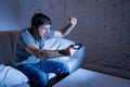 Young excited man at home sitting on living room sofa playing video games using remote control joystick Royalty Free Stock Photo