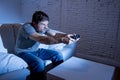 Young excited man at home sitting on living room sofa playing video games using remote control joystick Royalty Free Stock Photo