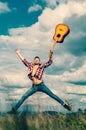 Young excited man jumping with guitar on nature background. Music outdoors. Sexy man with guitar in checkered shirt Royalty Free Stock Photo