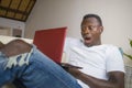 Young excited and surprised young black afro American man in disbelief and shock face expression networking with laptop computer Royalty Free Stock Photo