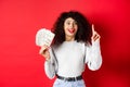 Young excited woman having an idea how make money, showing dollar bills and raising finger in eureka sign, standing on Royalty Free Stock Photo