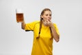 Young excited woman in yellow football kit holding beer mug and supports favorite team. Soccer fans, competition, sport Royalty Free Stock Photo