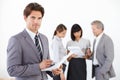 Young executive with a sharp business mind. Portrait of a handsome young executive holding documents while his team