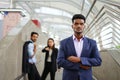 Young executive standing with arms crossed is suspiciously, background are employee talking about him as bullying Royalty Free Stock Photo