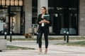 Young executive woman goes to office to work walking down a street