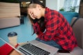 Young exhausted asian female IT employee with migraine touching head during work