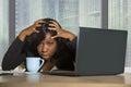 Young exhausted and depressed black afro American business woman working upset and sad at office computer desk by the window in ce