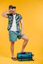 young exhausted male tourist standing on suitcase