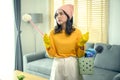 Young exhausted and tired housekeeper wearing yellow shirt in living room