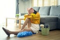 Young exhausted and tired housekeeper wearing yellow shirt in living room