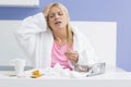 Young exhausted woman suffering from headache and cold in kitchen