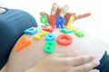 Young expectant mother with letter blocks spelling girl on her pregnant belly