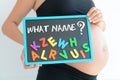 Young expectant mother with letter blocks spelling name on her pregnant belly