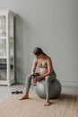 Young expectant tired woman breathing relax sit on fitness ball in living room. Royalty Free Stock Photo