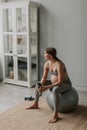 Young expectant tired woman breathing relax sit on fitness ball in living room. Royalty Free Stock Photo