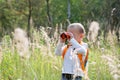 Young explorer watching with binoculars of birds in the high grass