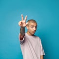 Young expressive emotional man showing three fingers gesture on blue background