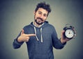 Young expressive happy hipster man holding alarm clock