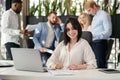 Young brunette female office worker looking at camera with lovely smile at her workplace in meeting room.