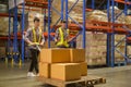 Young factory workers pulling a pallet truck between shelves full of packed boxes in warehouse, machinery and Logistics concept Royalty Free Stock Photo