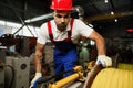 A young factory workman rolls heavy coil of electric cable