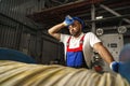 A young factory workman rolls heavy coil of electric cable