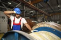 A young factory workman rolls heavy coil of electric cable