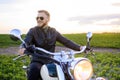 Young fair-haired brutal biker guy with a beard in sunglasses on a motorcycle