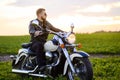 Young fair-haired brutal biker guy with a beard in sunglasses on a motorcycle