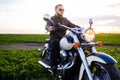 Young fair-haired brutal biker guy with a beard in sunglasses on a motorcycle