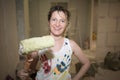 Young fair-haired curly woman makes repairs in the dwelling with construction tools.