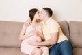 Young family. Attractive pregnant woman and man resting on bed and kissing. Happy pregnant family Royalty Free Stock Photo