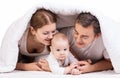 Young family with baby boy under blanket on bed Royalty Free Stock Photo