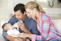 Young Family With Baby Feeding On Sofa At Home Royalty Free Stock Photo