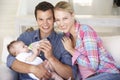 Young Family With Baby Feeding On Sofa At Home Royalty Free Stock Photo
