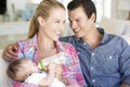 Young Family With Baby Feeding On Sofa At Home Royalty Free Stock Photo