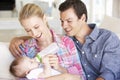 Young Family With Baby Feeding On Sofa At Home Royalty Free Stock Photo