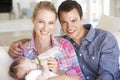 Young Family With Baby Feeding On Sofa At Home Royalty Free Stock Photo