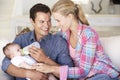 Young Family With Baby Feeding On Sofa At Home Royalty Free Stock Photo